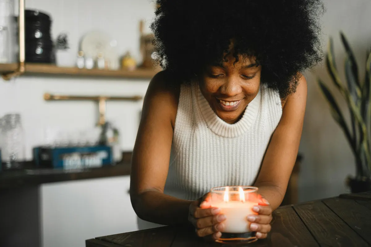Person holding a candle in a calm, restorative setting.